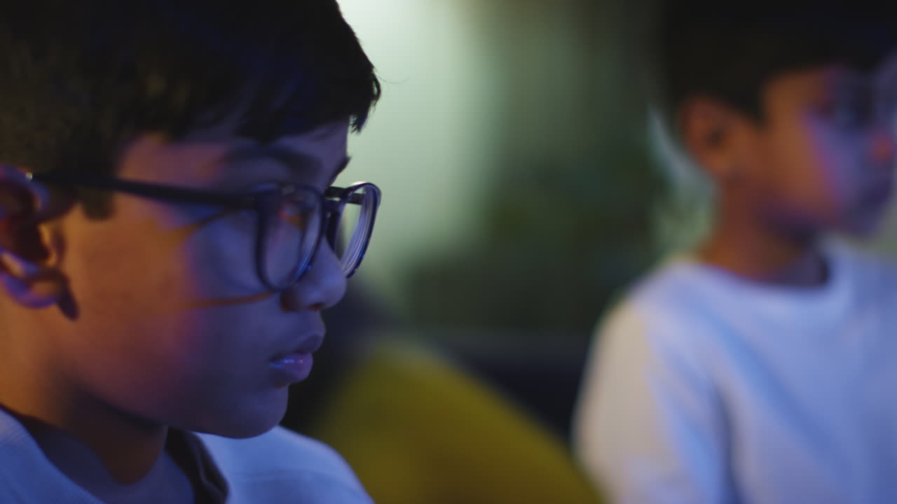 Close Up Of Two Young Boys At Home Playing With Computer Games Console On TV Holding Controllers Late At Night 8