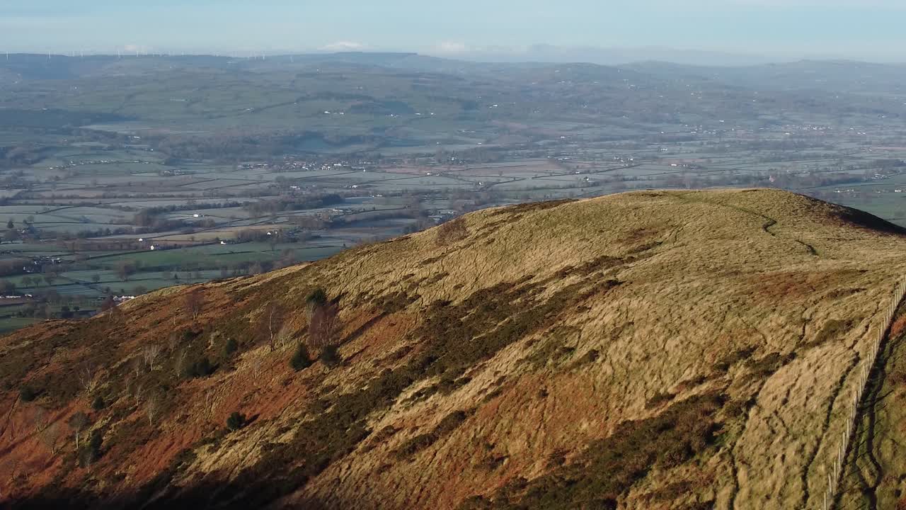 la primera luz del sol en el pico de la montaña de las tierras altas vista aérea a través de vastas tierras de cultivo idílicas y heladas reversa a la izquierda