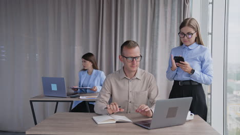 young office team working together. lady comes up to her colleagues holding a folder in her hands.