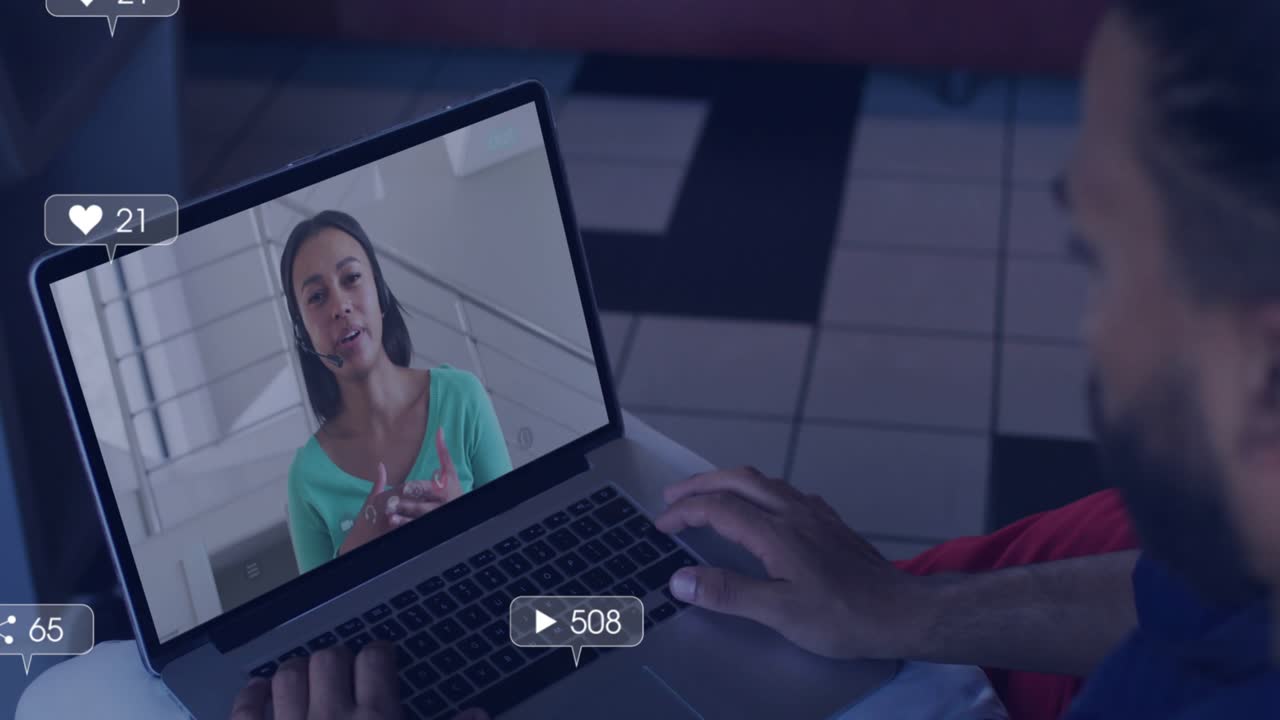 Man typing, watching colleague speaking on screen tech demo, social media icons rising then fading