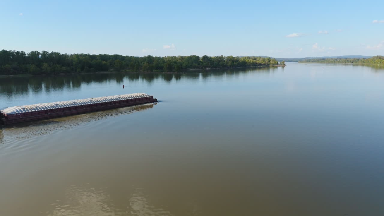 Aerial approach to slow moving barge along Arkansas River at midday