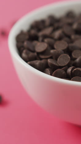 video de primer plano de un cuenco de trozos de chocolate sobre un fondo rosado