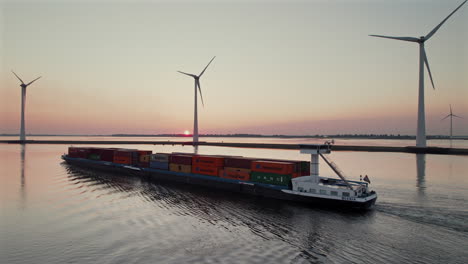 cargo ship sailing along the wind turbines at krammer lake during sunset in bruinisse, netherlands. - aerial shot