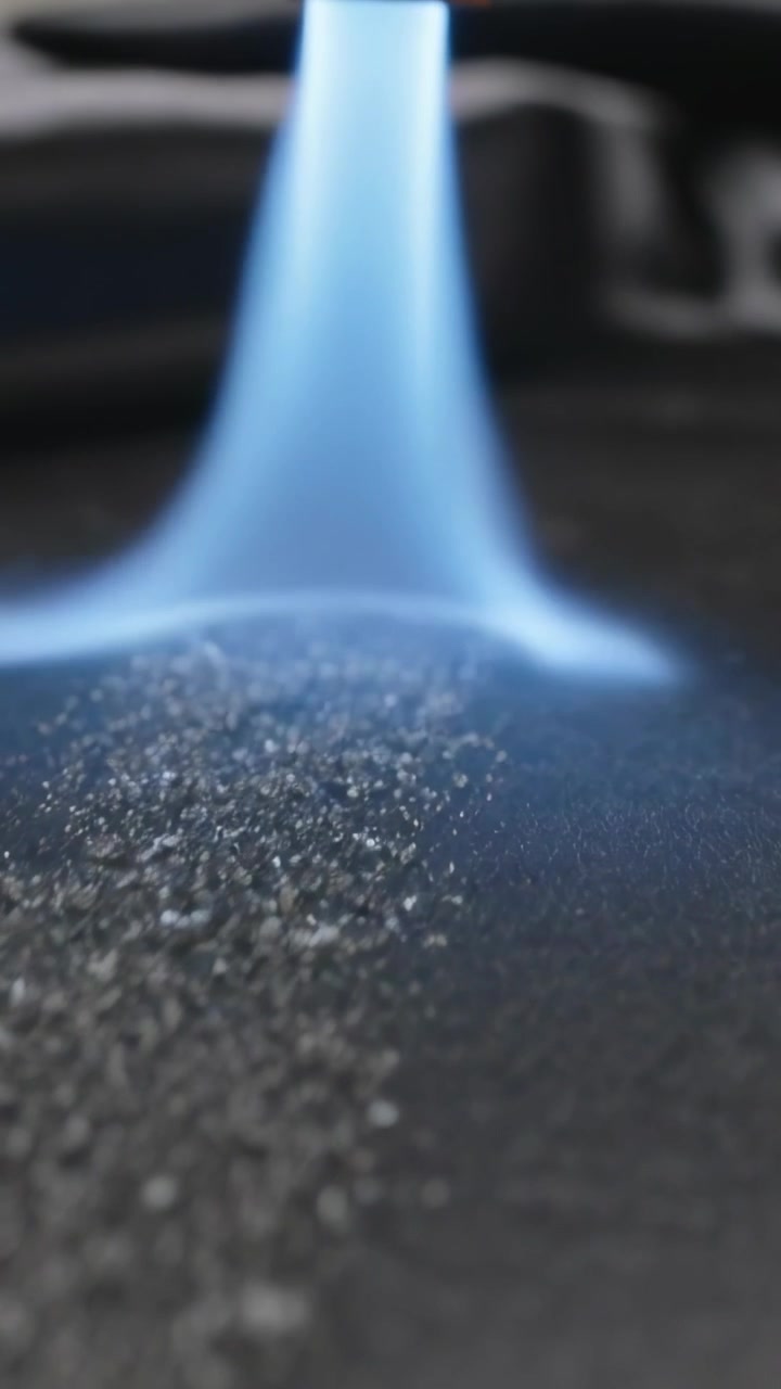 Vertical video: Projecting blue plasma column from nozzle onto dark mat, causing powder to brighten