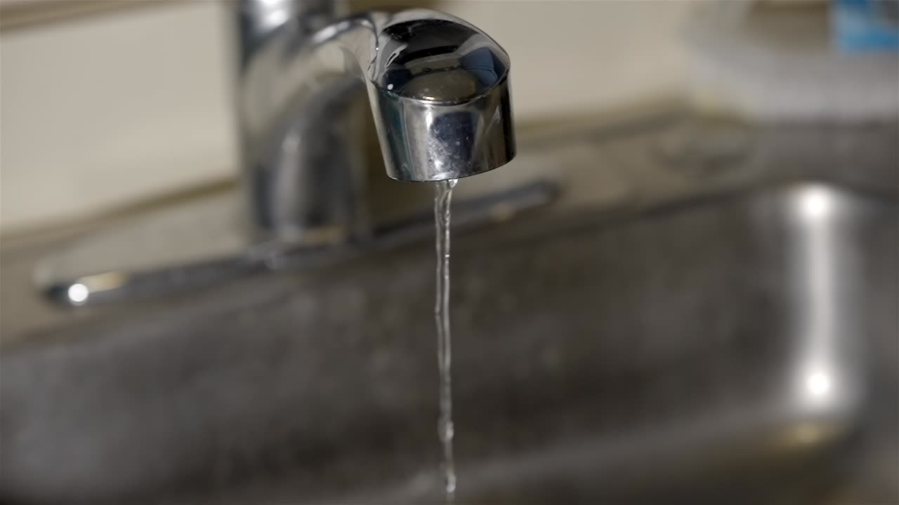 Wasting Water Concept: Running Faucet in Stainless Sink