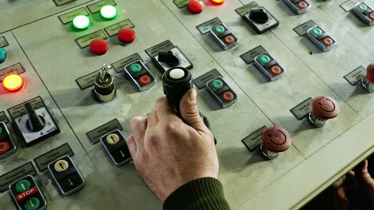 Close-up of worker’s hand using joystick on retro control panel at terminal