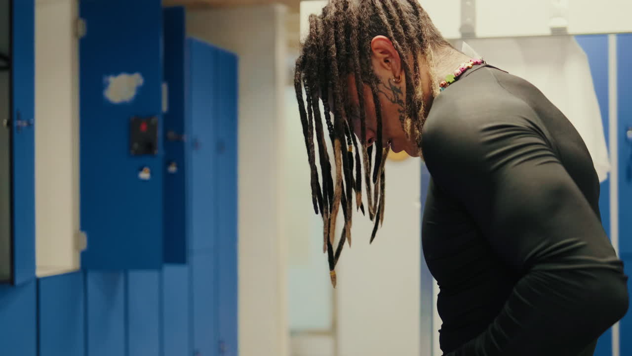 Person with Dreadlocks Bending Over in a Locker Room