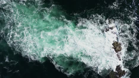 topdown view ocean waves breaking on submerged rocks, sea foam on beep sea