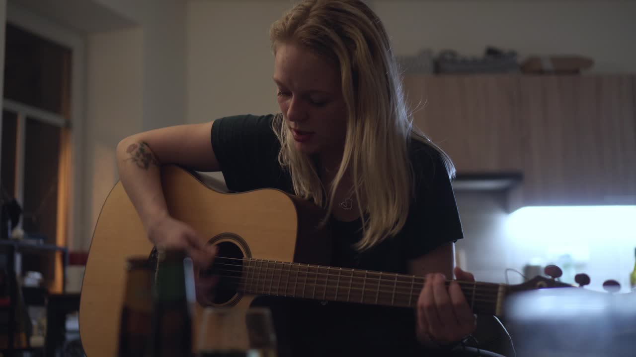 Smuk blond pige spiller guitar, lærer at spille derhjemme
