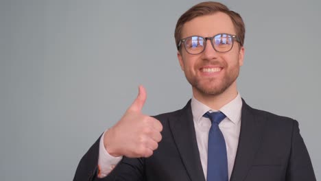a man dressed in business clothes is looking intently at the camera and giving thumbs up european man dressed in business clothes is looking at the camera with concentration and giving a thumbs up handsome office manager on the background in the studio video