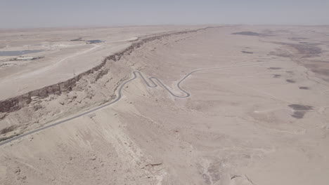 Vista-Aérea-De-Una-Hermosa-Zona-Desértica-Seca-Con-Un-Camino-Sinuoso-Que-Sale-De-Un-Cráter