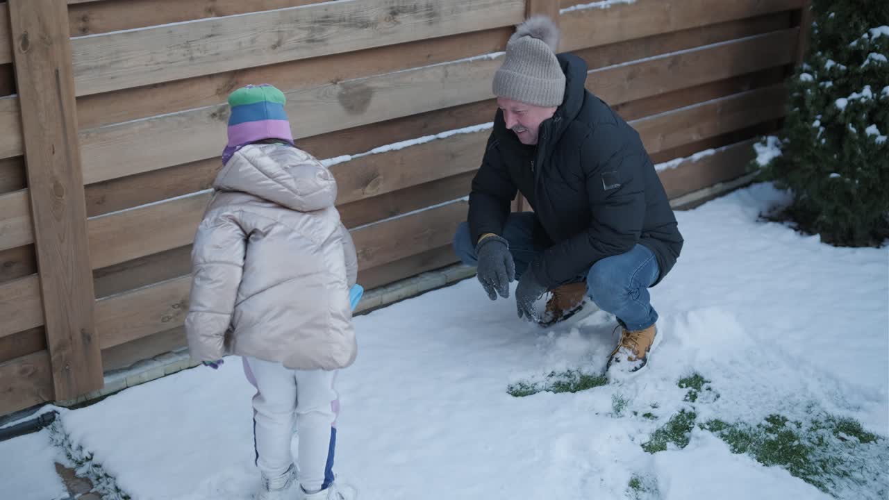 할아버지와 손녀가 눈 속에서 재미를 느끼고 있습니다.