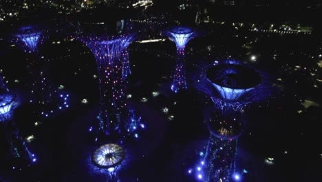 drone video orbiting around the supertree grove at gardens by the bay in singapore with color-changing lights