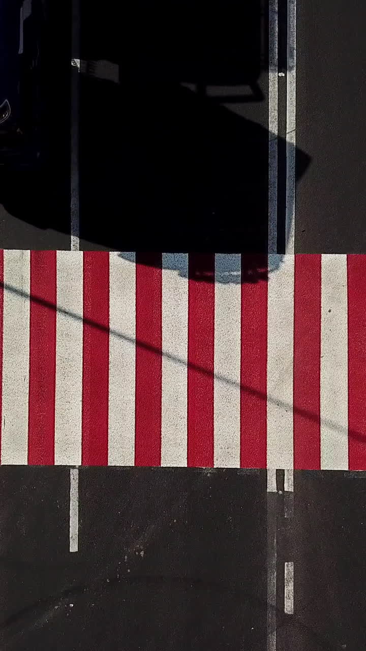 cars are quickly passing a pedestrian crossing in the street of city. Fast traffic cars. Camera motion to up. Aerial view Vertical video