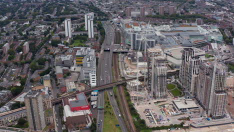 High-angle-view-of-multilane-highway-leading-through-urban-neighbourhood.-Static-shot-of-construction-site-of-new-tall-apartment-buildings.-London,-UK