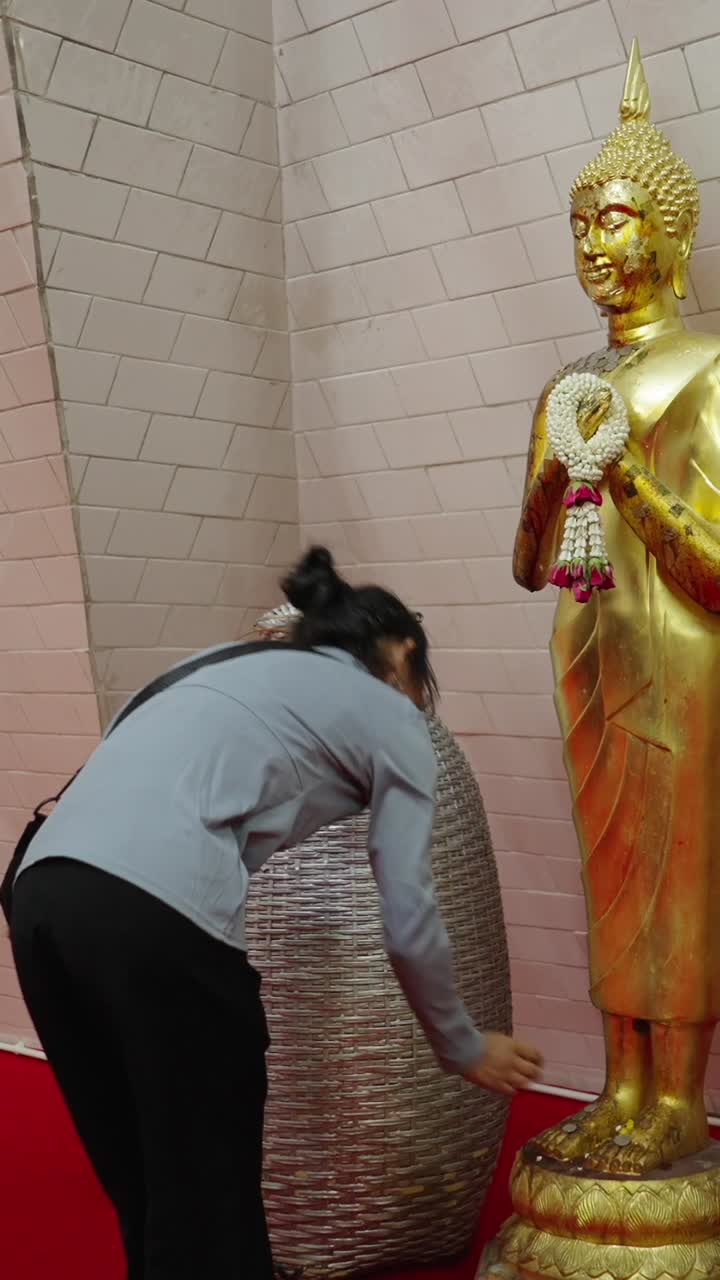 Woman praying in front of Buddha statue