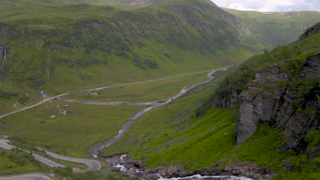 aerial shot flying through a mountain valley with a river and road in norway