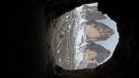 Creative-medium-shot-of-man-passing-WWI-cave-opening-in-Italian-Dolomites