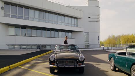 woman standing near a vintage car in front of a modern building