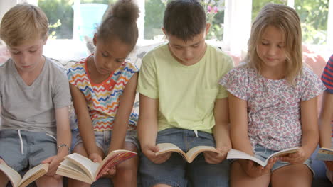 Gruppe-Multikultureller-Kinder,-Die-Auf-Dem-Fensterplatz-Lesen