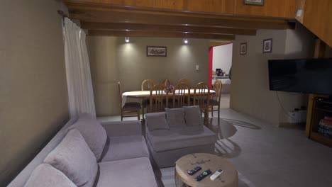 slow right panning clip of cozy wooden house living and dining room, with couch and surroundings in grey and brown tones. shot on 4k.