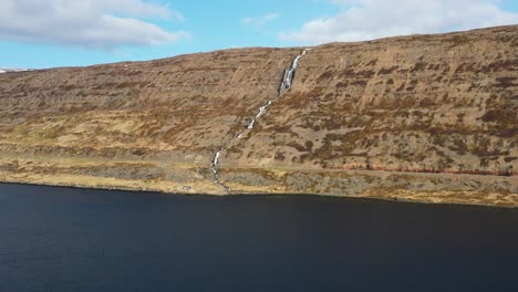 Luftaufnahme-Von-Wasser,-Das-über-Einen-Wasserfall-In-Einer-Trockenen-Bergwand-In-Island-Fällt