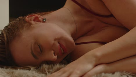 retrato de una joven atractiva que se acuesta en una alfombra de piel y acaricia sensualmente su cara y cuerpo