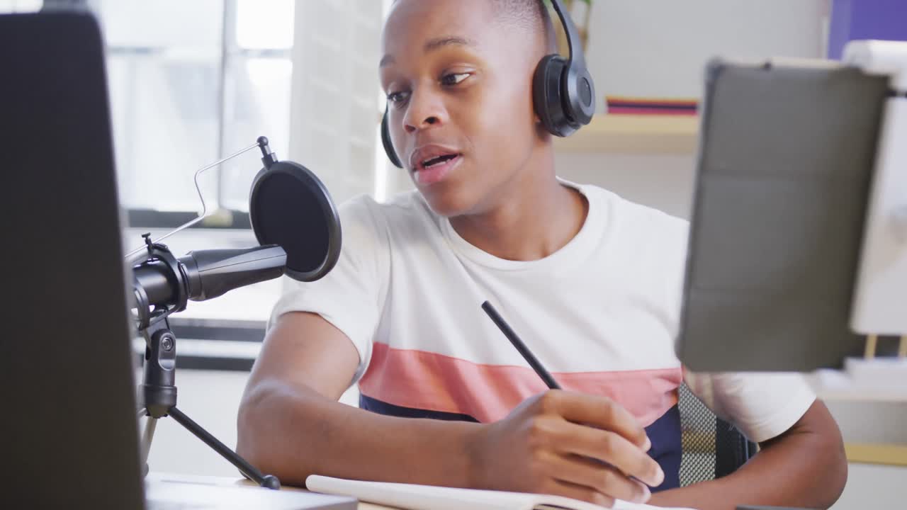 un adolescente afroamericano feliz grabando un podcast usando una computadora portátil, en cámara lenta