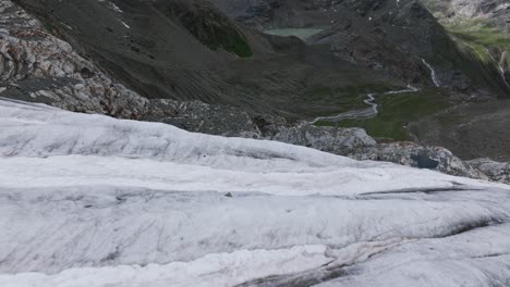 Drone-flying-at-low-altitude-over-surface-of-Fellaria-Glacier-with-valley-in-background,-Valmalenco-in-Italy