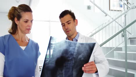 el médico y la enfermera discuten sobre el informe de rayos x en el pasillo.