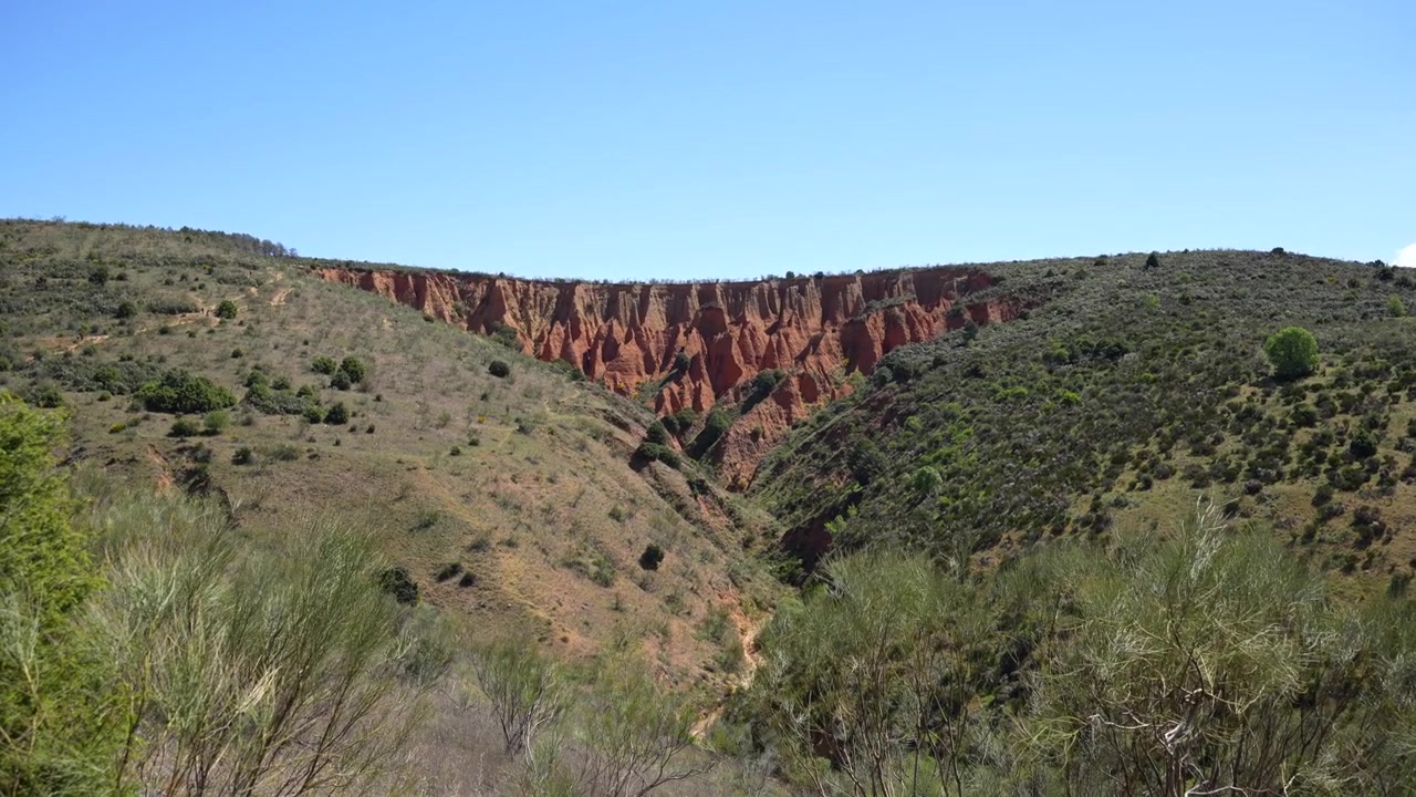 Rocce rosse naturali nel mezzo di uno splendido paesaggio verde, cielo blu e giornata soleggiata. Ripresa a mano