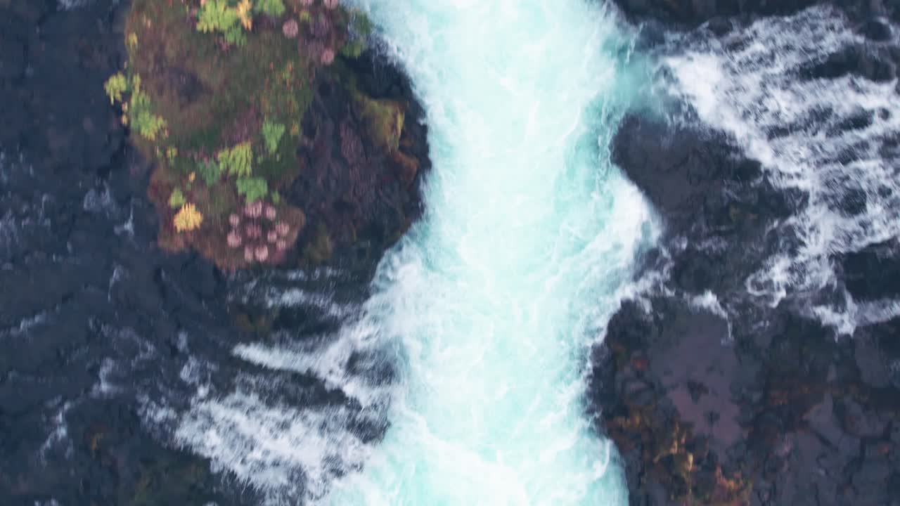 aerial: vista de arriba hacia abajo de cerca de la cascada de bruarfoss y la piscina de inmersión en el sur de islandia que es muy pintoresca con la hermosa cascada azul de cataratas