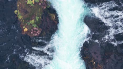 aerial: top down close view of bruarfoss cascading waterfall and plunge pool in southern iceland that is very picturesque with the beautiful blue cascade of falls