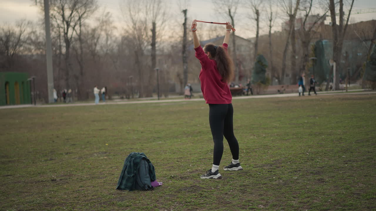 Caucasian Woman Dancing, Elegant Woman Swings Ribbon Gracefully, Graceful Lady Performs Ribbon Dance Outdoors, Caucasian Woman Displays Coordinated Ribbon Movement Amidst Sunlit Open Field