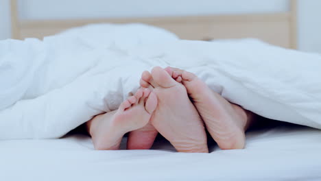 couple, feet and together in bed on holiday