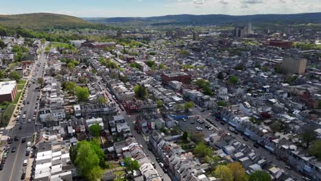 High-angle-flight-over-american-town-with-green-mountains-landscape-in-background