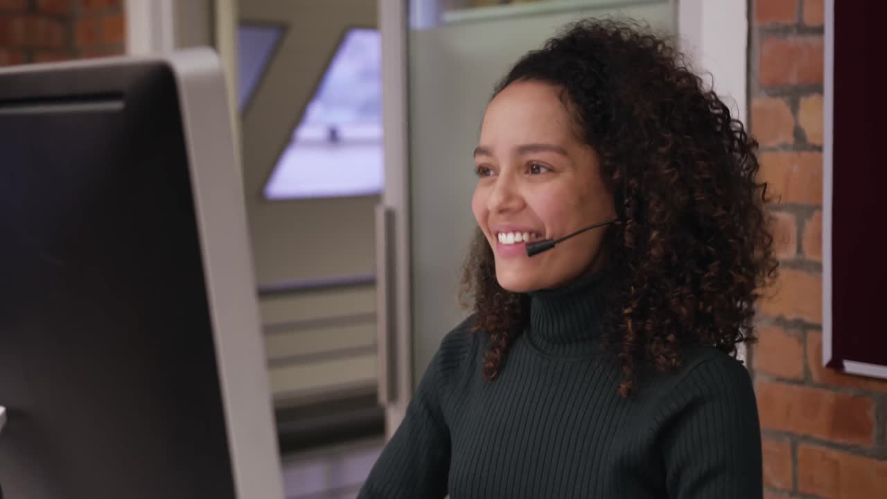 Donna d'affari creativa che parla con un auricolare in un ufficio moderno.