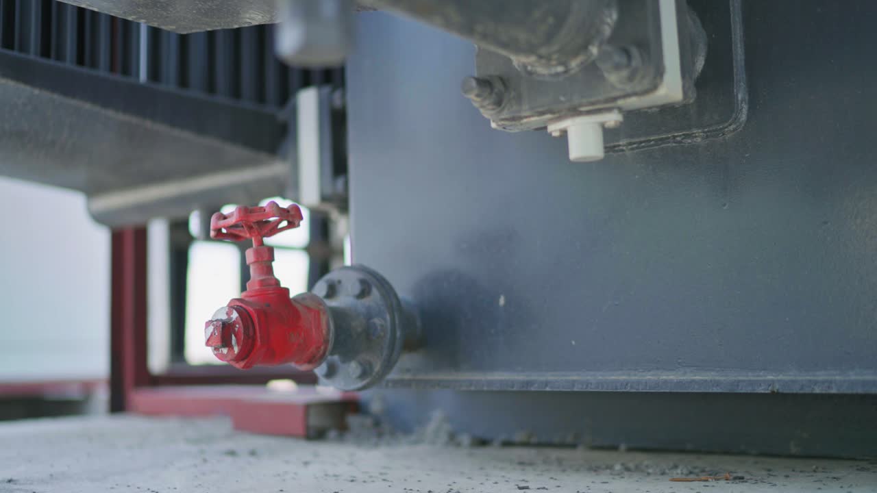 Closeup view of a red gate valve attached to a industrial equipment