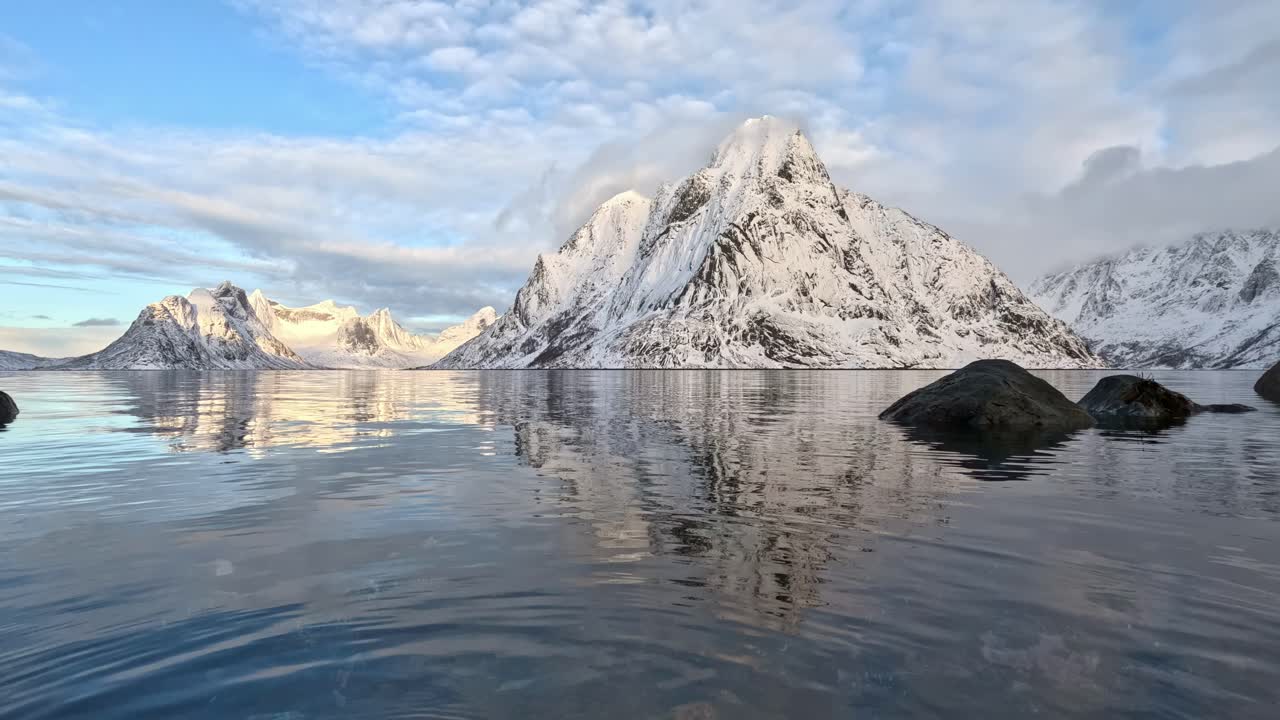Olstinden em Lofoten no inverno, em ângulo baixo perto da superfície do mar com água em movimento