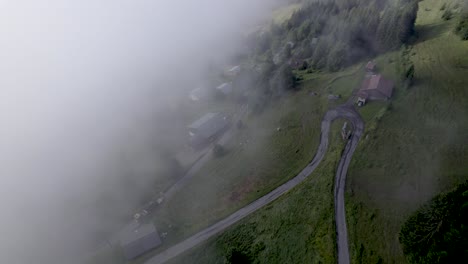 Aerial-of-Mont-Chery-mountain-slope-with-green-meadows-and-pine-trees-seen-through-cloud-obscuring-half-of-the-scenery