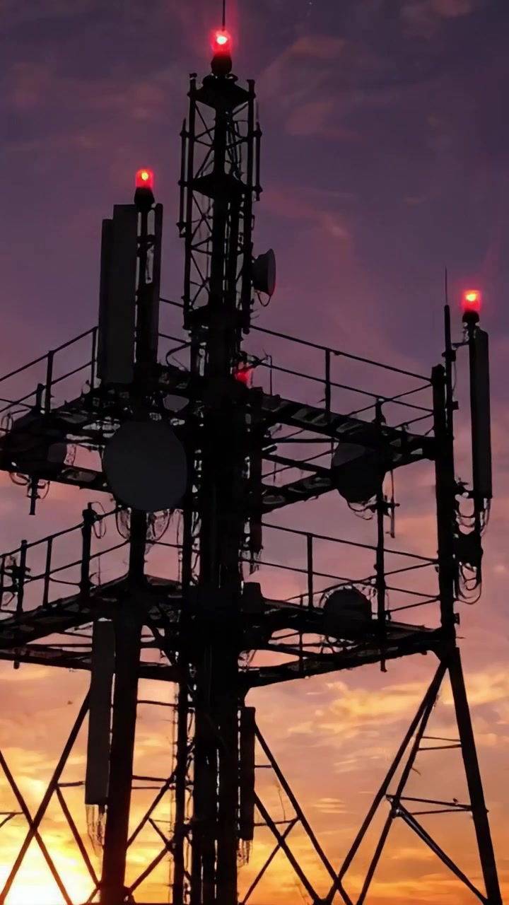 Torre di telecomunicazioni in silhouette contro un cielo vibrante al tramonto: una bella fine della giornata con le luci della torre che illuminano l'orizzonte e colori vivaci nell'atmosfera.