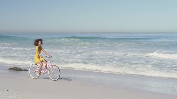 African American woman riding a bike seaside