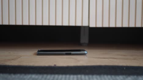 phone under a cabinet on a wooden floor