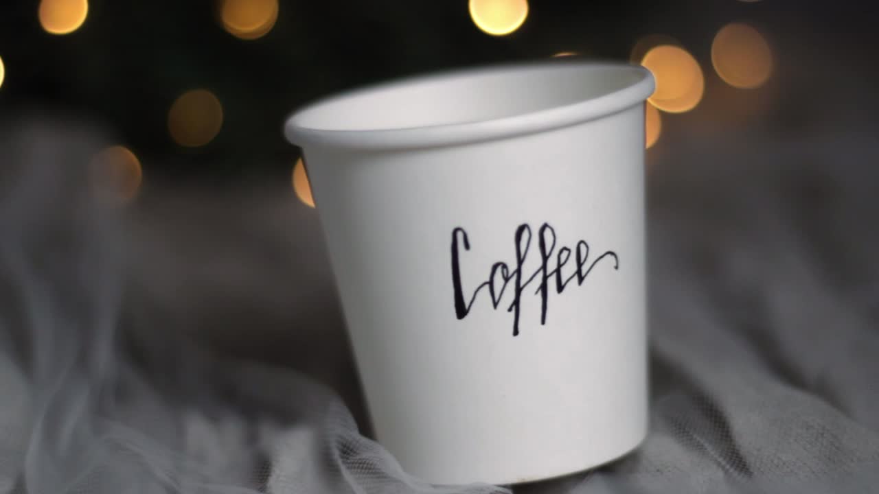taza de papel de café de navidad en una cama acogedora con bokeh, primer plano