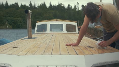 carpenter wiping sanded roof of wooden boat