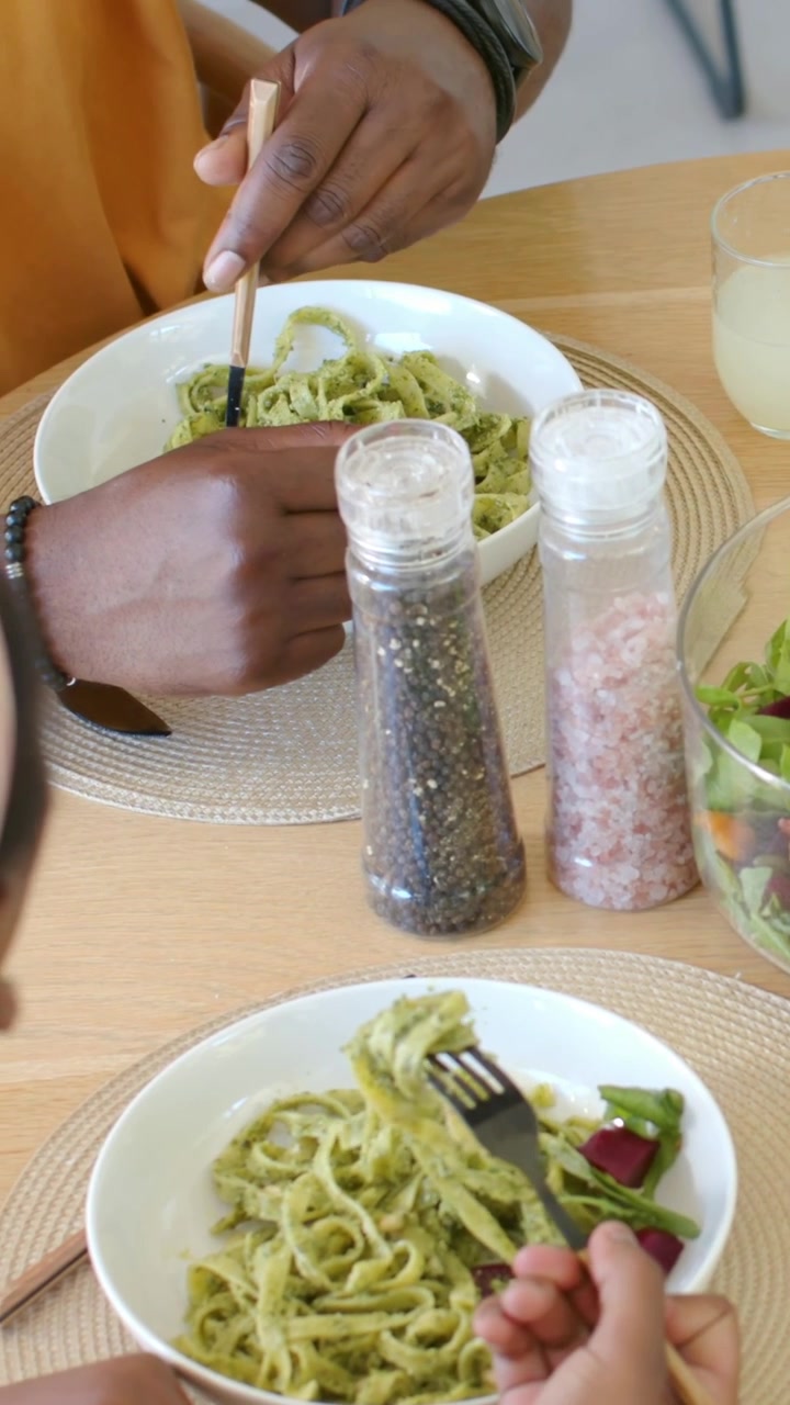 Vertical video: Starting meal man stirring communal bowl with chopsticks to serve child at home