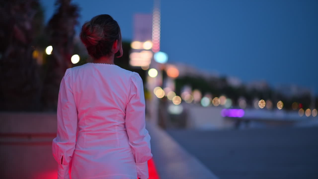 Woman in white dress walking in Cannes embankment street, France