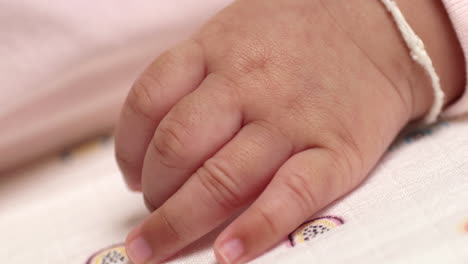 close-up shot of the hand of a newborn baby showing her fingers and a bracelet on her wrist