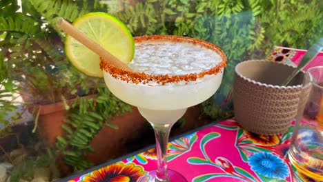 Cóctel-Picante-De-Margarita-Mezcalita-Con-Tajín-Y-Una-Rodaja-De-Lima-En-Un-Restaurante-Mexicano,-Bebida-Popular-De-Fiesta,-Toma-De-4k