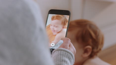 mother taking photo of baby using smartphone enjoying photographing cute toddler sharing motherhood lifestyle on social media